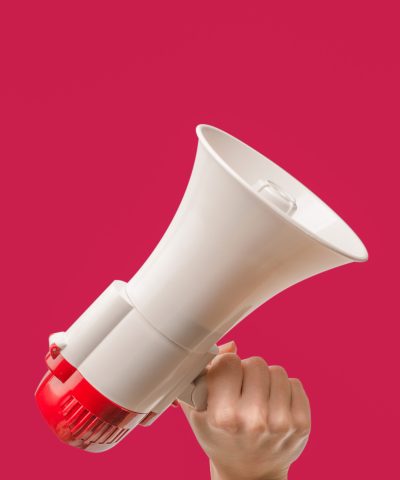 Megaphone in woman hands on a viva magenta background.  Copy space.